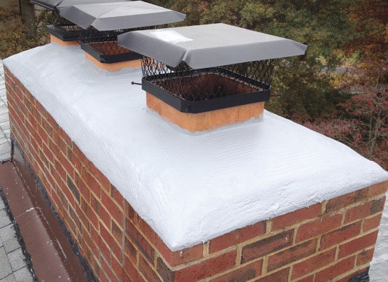 A freshly sealed white chimney crown on a brick chimney
