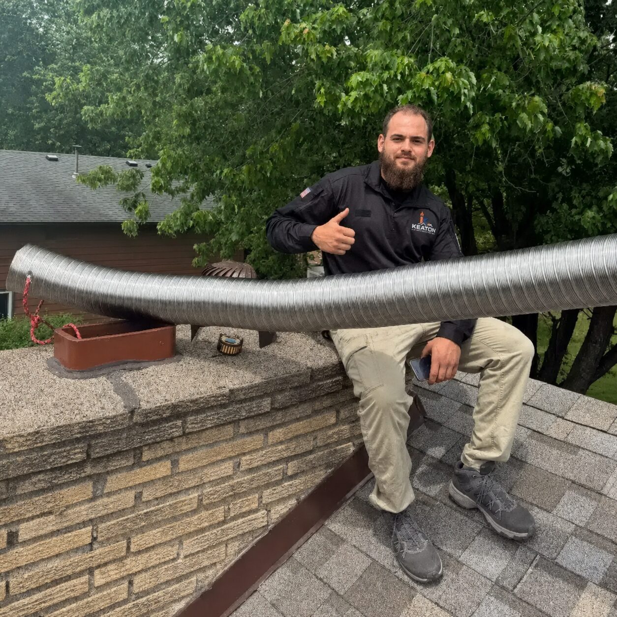 Technician feeding a stainless chimney liner from the roof